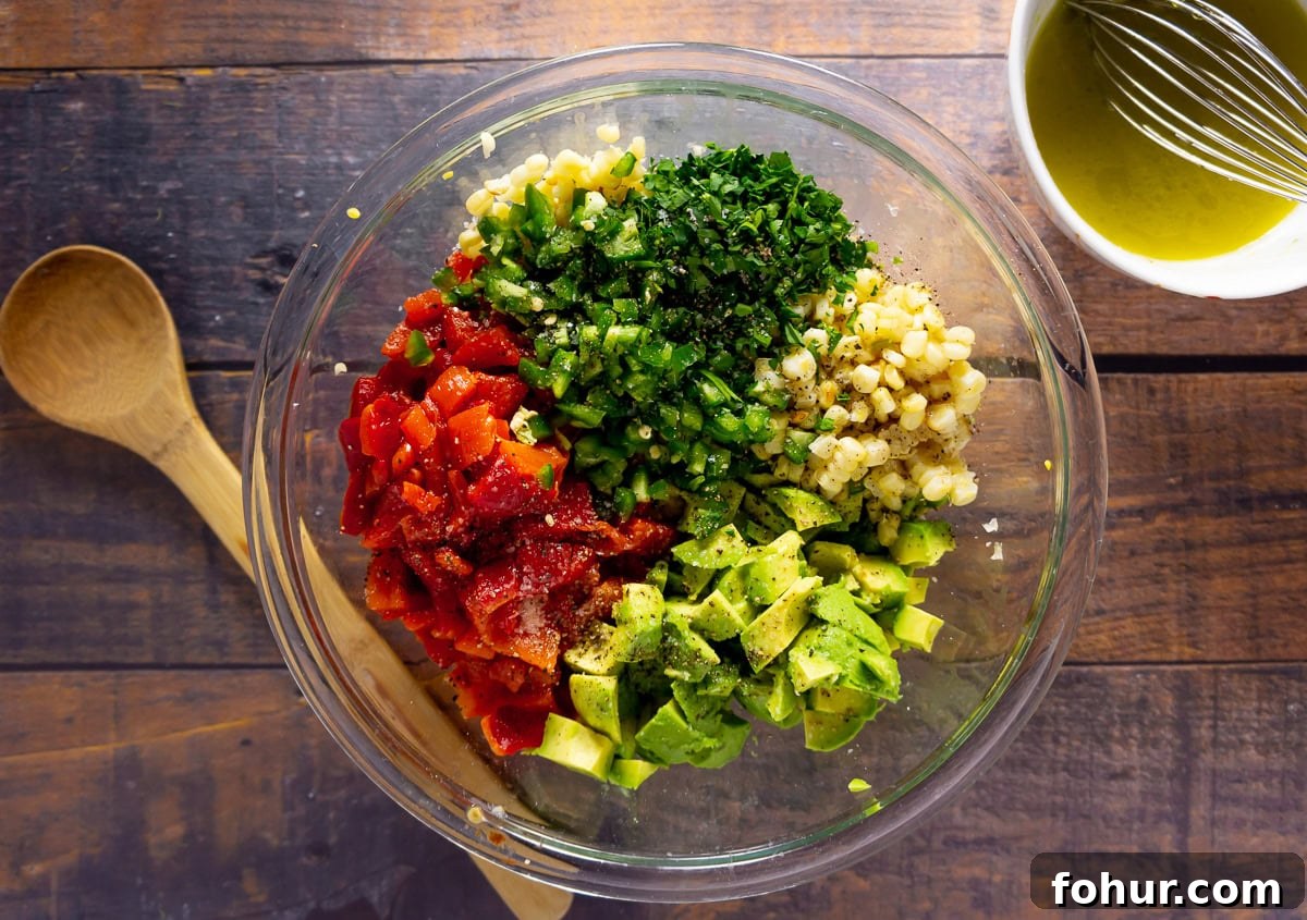 a bowl of chopped corn, avocado, peppers, jalapenos, and herbs