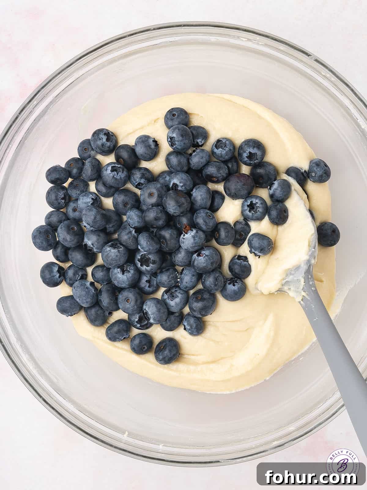 With fresh blueberries and sour cream, this Blueberry Coffee Cake is moist and tender, with an irresistible sweet & crunchy streusel topping. Fresh blueberries being folded into cake batter