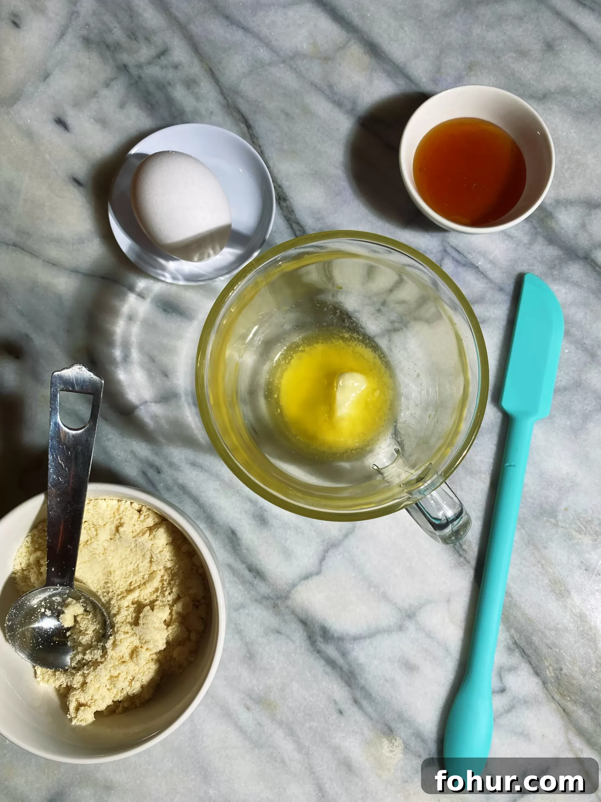 Almond Flour Mug Cake: Low-Carb Keto Microwave Dessert 2 Overhead shot of the butter melted in mug, honey to the upper right, a whole egg to the top left and almond flour corner left.