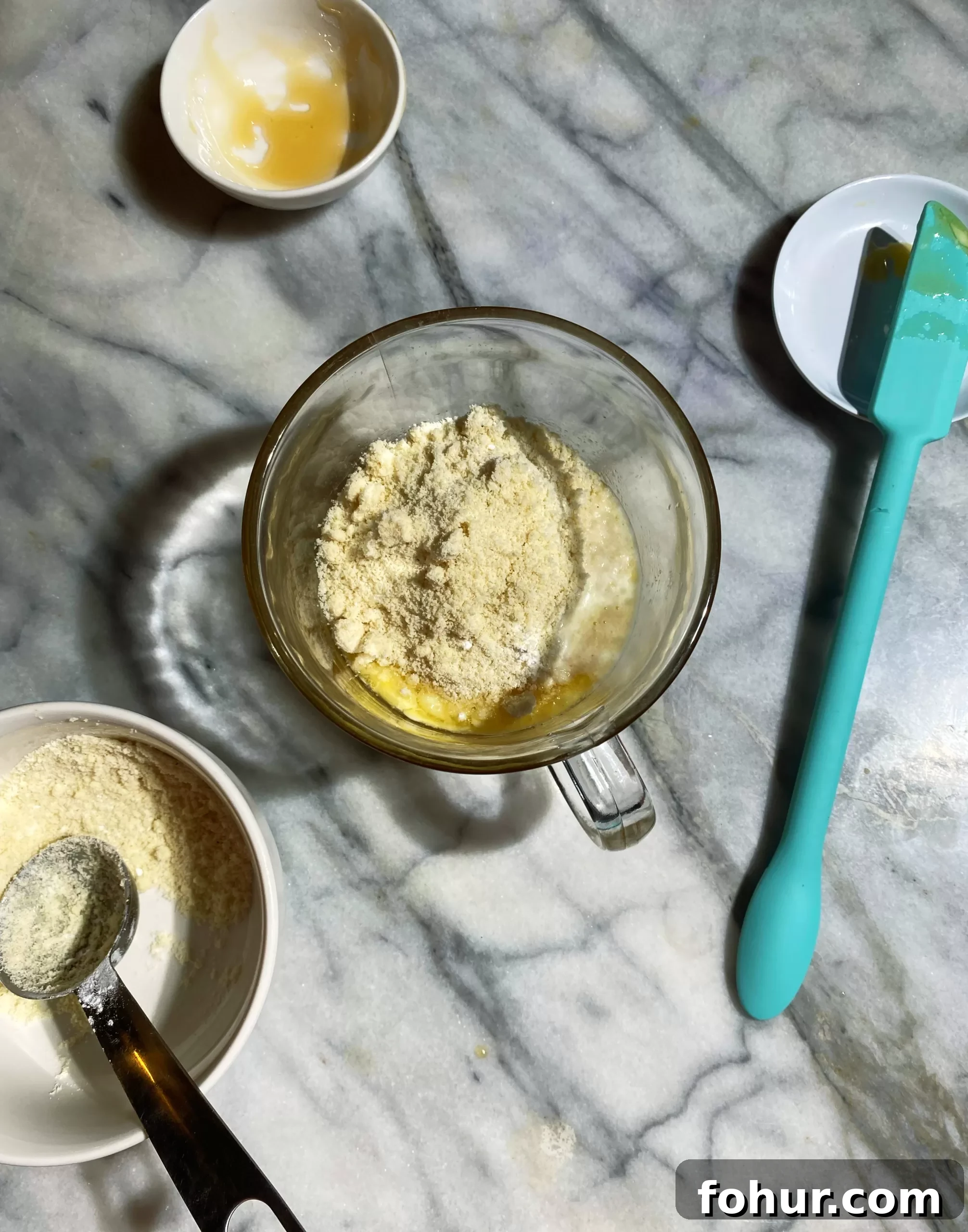 Almond Flour Mug Cake: Low-Carb Keto Microwave Dessert 3 Overhead shot of the dry ingredients being added to the wet in a glass mug.