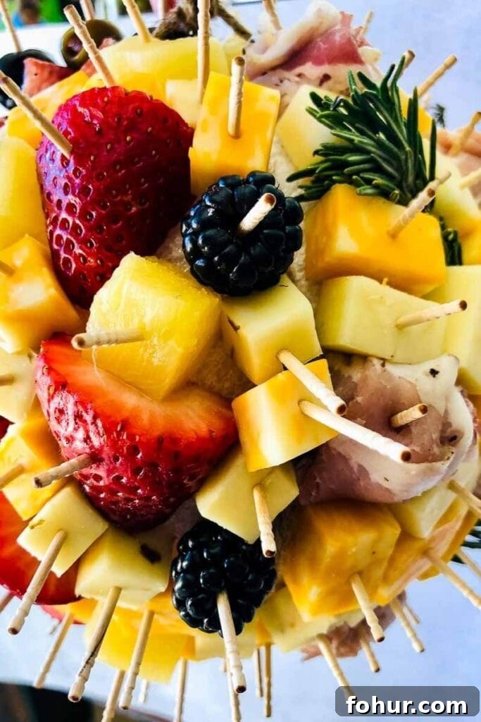 Charcuterie Ball Drop: Creative Party Centerpiece 5 Close up view of fruit and cheese on toothpicks stuck in the charcuterie ball.
