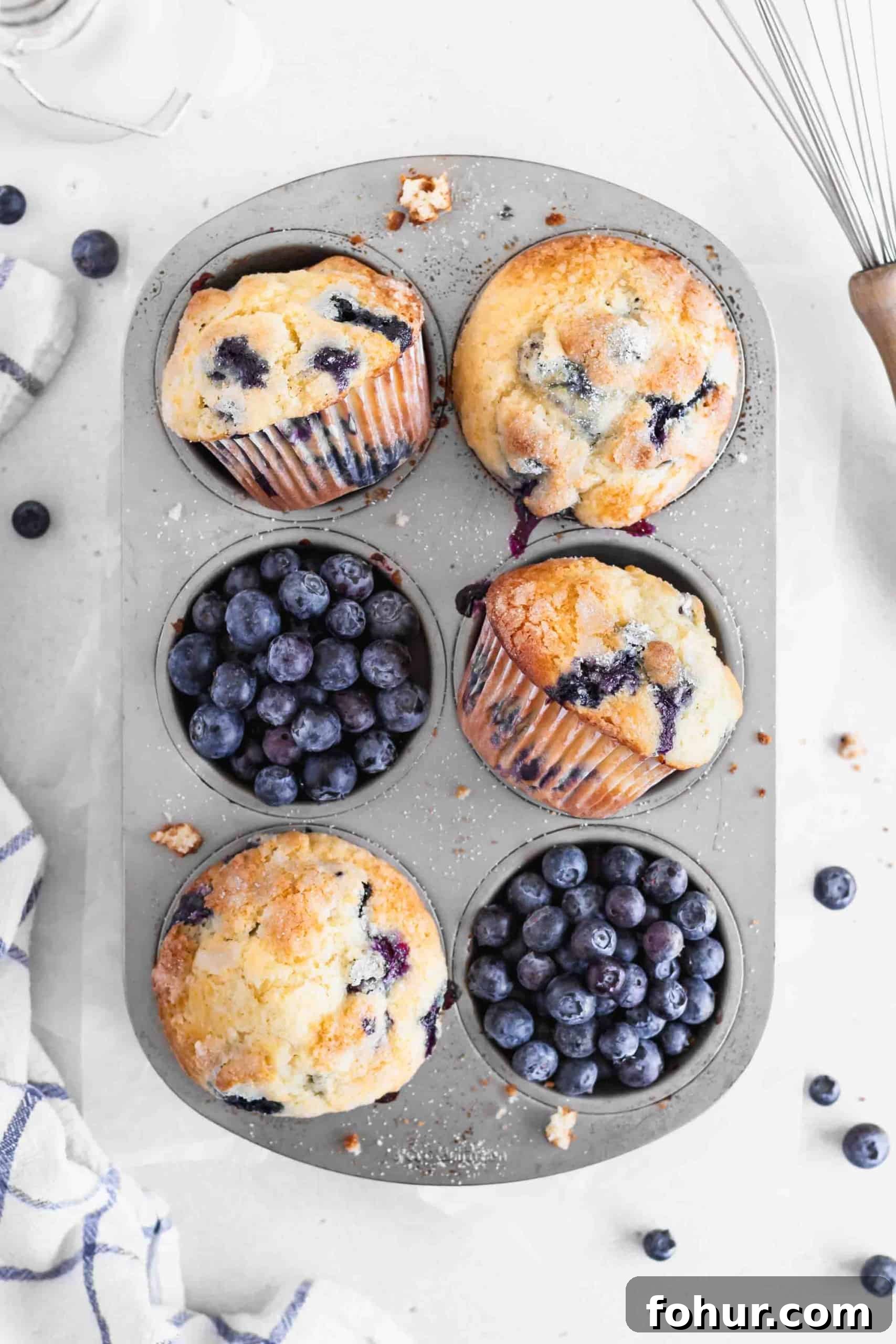 Classic Blueberry Muffins Recipe with Fresh Berries 2 Blueberry muffins and fresh blueberries in a muffin pan