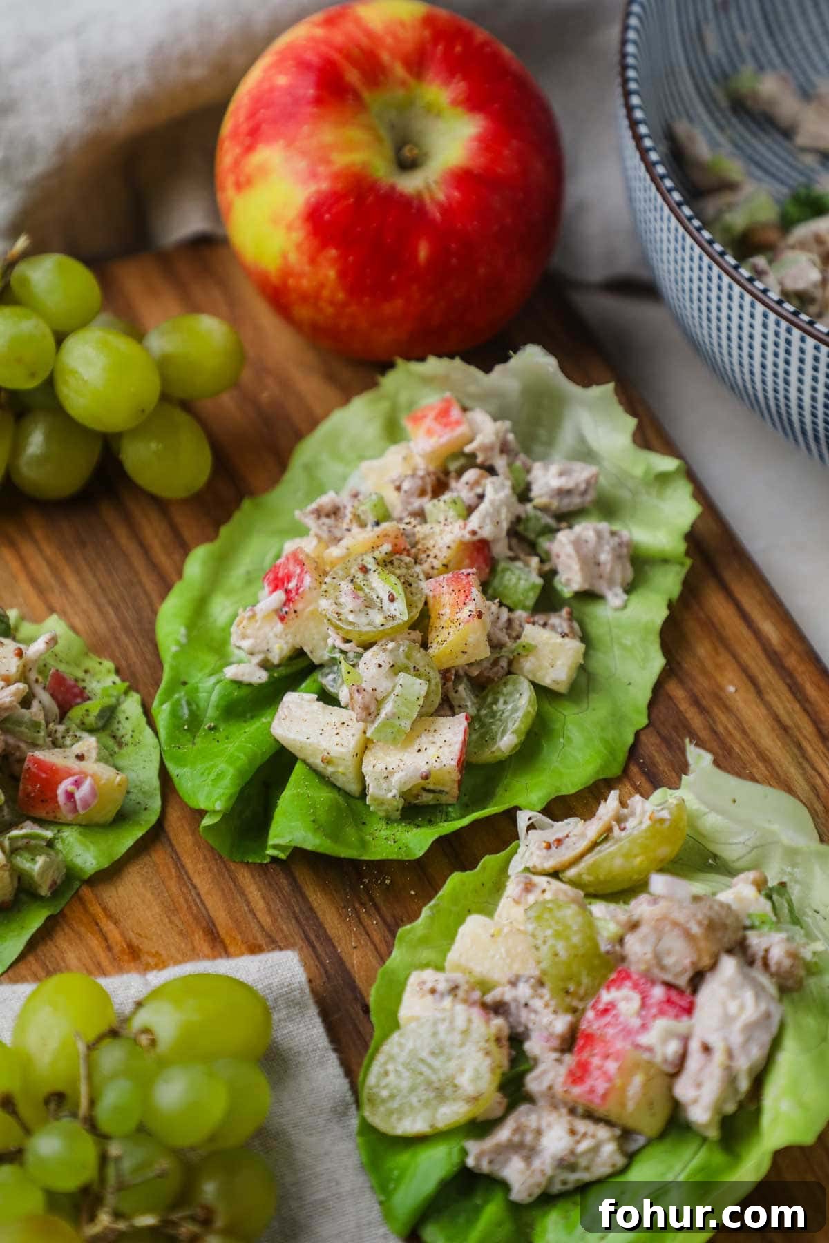 Chicken Salad Lettuce Wraps Recipe with Crisp Veggies 2 Healthy chicken salad lettuce wrap cups served on a wooden board for a delicious, satisfying lunch.