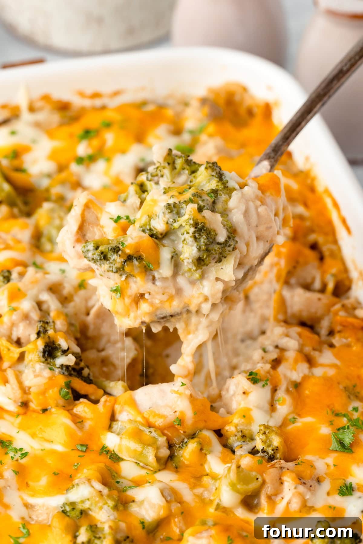 Creamy Cheesy Chicken Broccoli and Rice Casserole 2 A close-up of a Cheesy Chicken Broccoli and Rice Casserole being served from a white baking dish, with melted cheese, tender chicken, broccoli, and fluffy rice clearly visible.