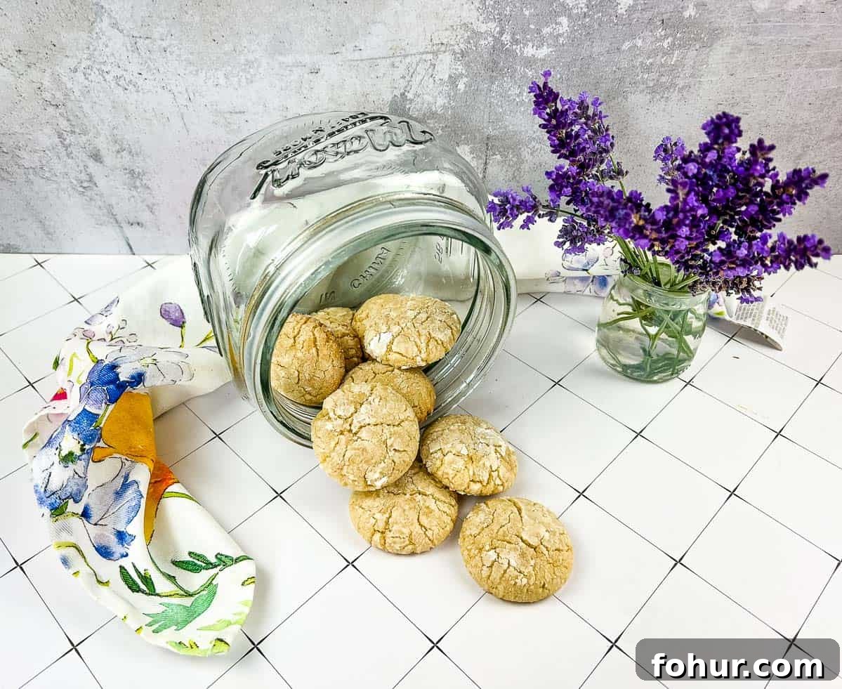 19 Cookie Recipes Even Dessert Skeptics Can't Resist 11 A jar of White Chocolate Crinkle Cookies next to lavender flowers.