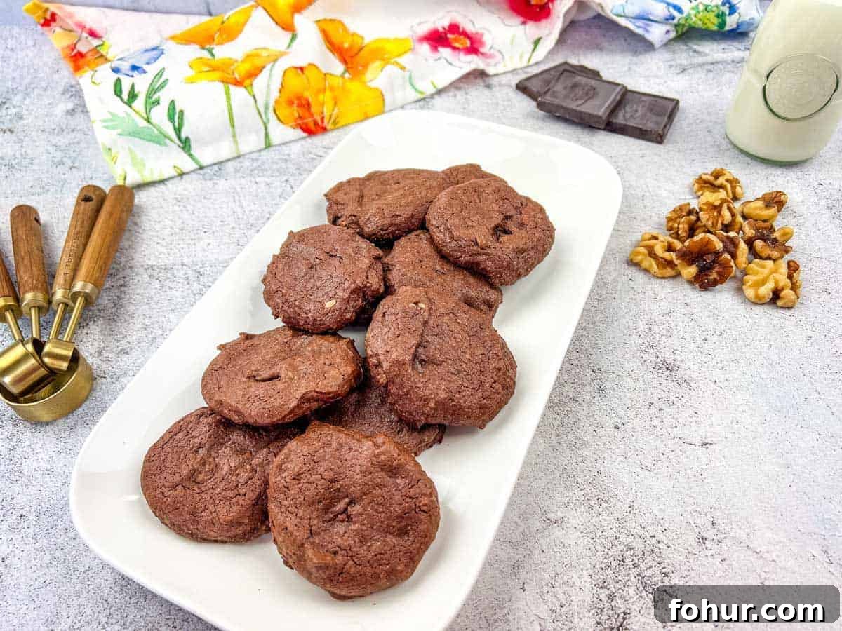 19 Cookie Recipes Even Dessert Skeptics Can't Resist 7 A plate of chocolate cookies with walnuts and chocolate pieces on the side.