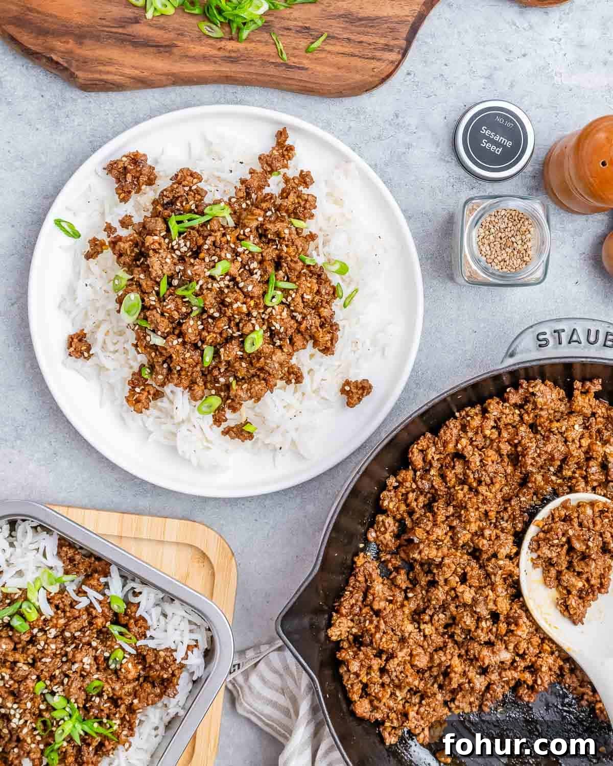 A plate of ground beef and rice with a skillet and serving spoon on the side.