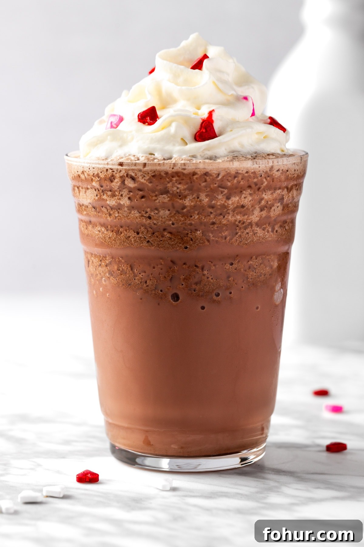 A red velvet frappuccino topped with whipped cream on white background.