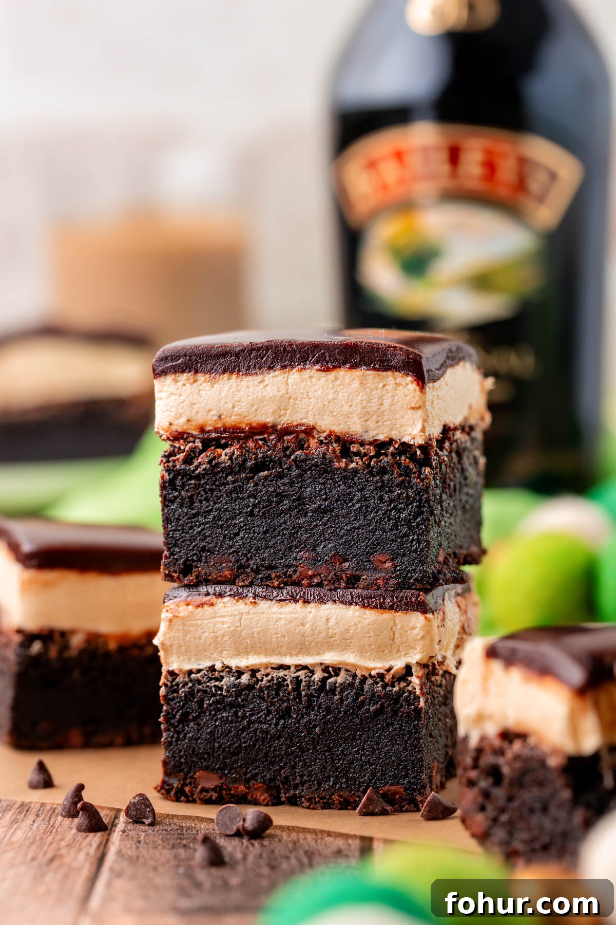 Decadent Baileys Irish Cream Brownies Recipe 7 Two brownies with irish cream frosting and ganache topping stacked on a piece of parchment paper.