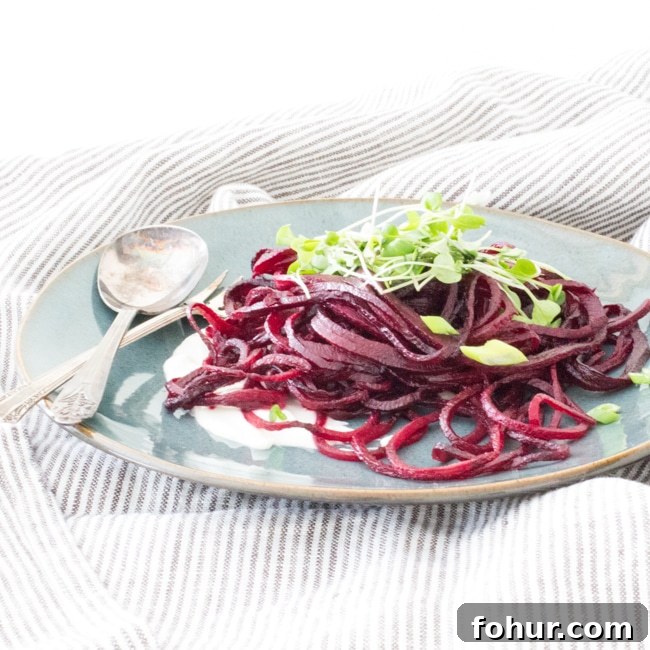 Spiralized Beet Noodle Salad with Creamy Whipped Feta 3 Side angle view of beet pasta noodles (spiralized beets) on whipped feta with broccoli sprout on top.