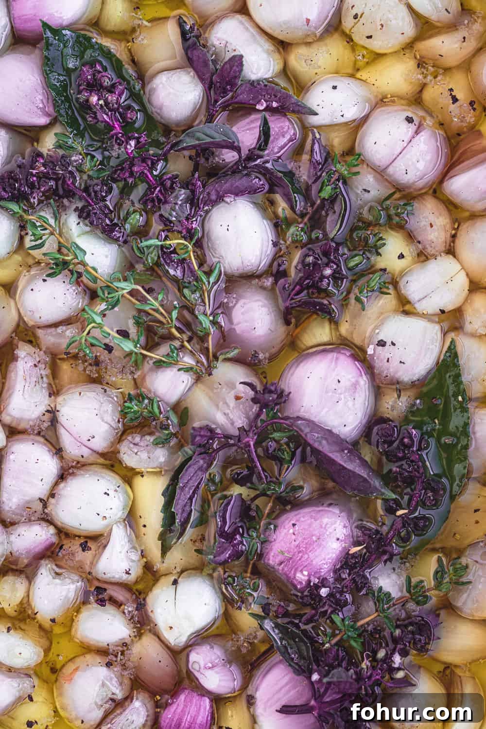 Shallot Confit Recipe: Jammy Slow-Roasted Condiment for Any Dish 4 Raw shallots submerged in olive oil with fresh herbs before roasting for shallot confit.