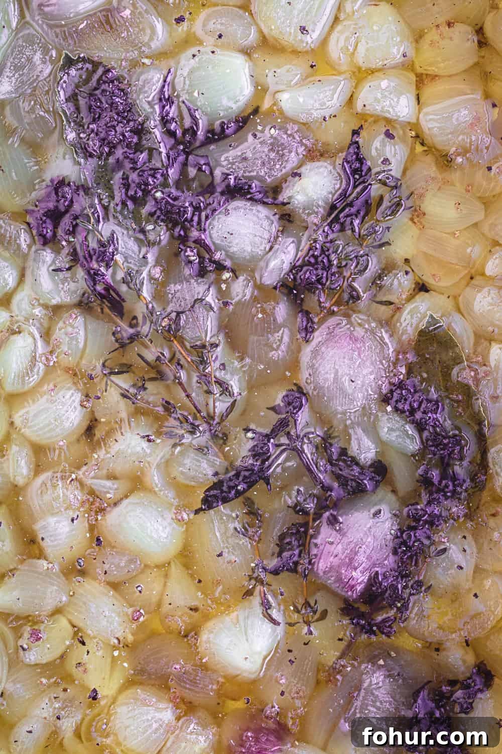 Shallot Confit Recipe: Jammy Slow-Roasted Condiment for Any Dish 5 Shallot confit just out of the oven, with softened shallots in olive oil and fresh herbs.